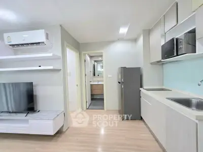 Modern open-plan living room and kitchen with sleek appliances and minimalist design.