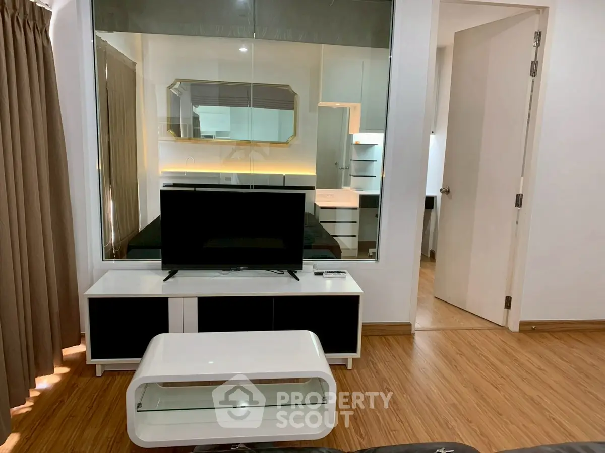 Modern living room with sleek furniture and glass partition, showcasing a stylish interior design.