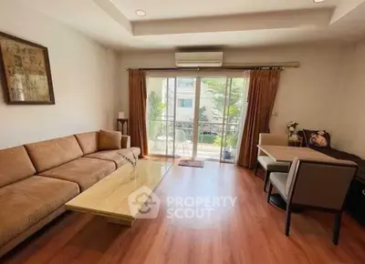 Spacious living room with large sofa and balcony view, perfect for relaxation.