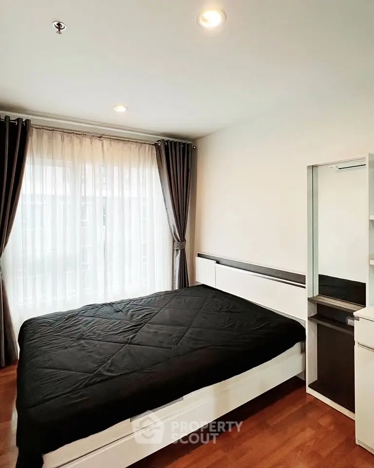 Modern bedroom with large window and stylish curtains, featuring a sleek bed and wooden flooring.