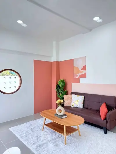 Stylish living room with modern decor, featuring a cozy sofa, round window, and elegant coffee table.