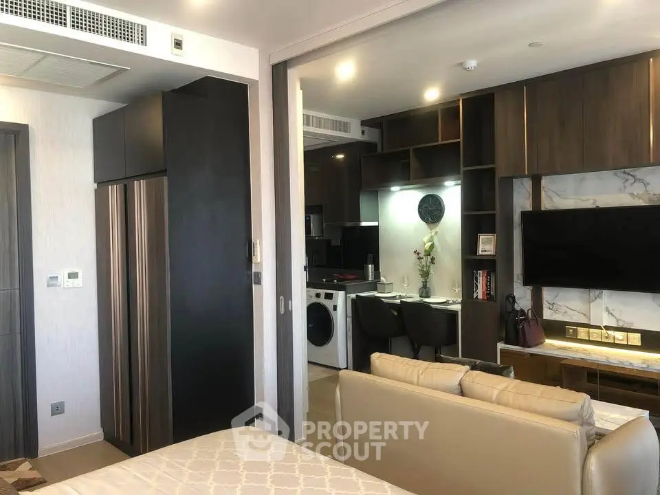 Modern open-plan living room with kitchen, featuring sleek appliances and stylish decor.