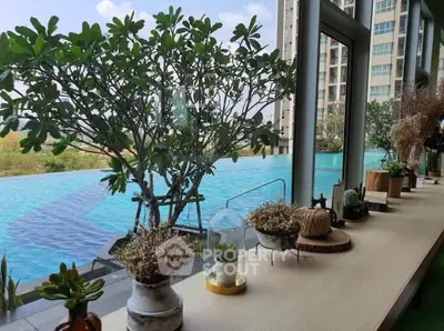 Luxurious poolside view with lush greenery and modern high-rise building, perfect for relaxation and leisure.