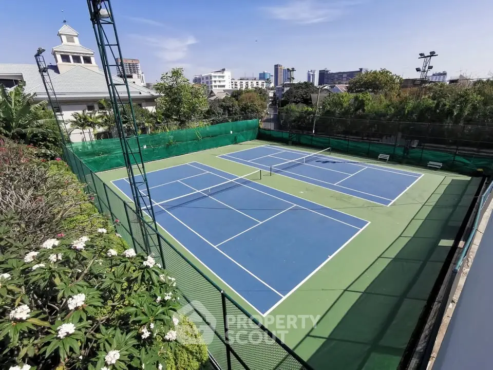Luxurious residential complex with tennis court and lush greenery