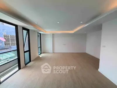 Spacious modern living room with large windows and wooden flooring, perfect for natural light lovers.