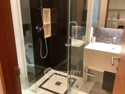 Modern bathroom with glass shower and sleek vanity in contemporary apartment.