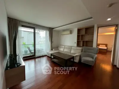 Spacious living room with hardwood floors and balcony access in modern apartment.