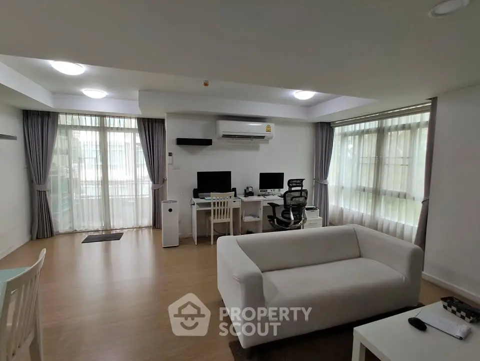 Spacious modern living room with work-from-home setup and natural light