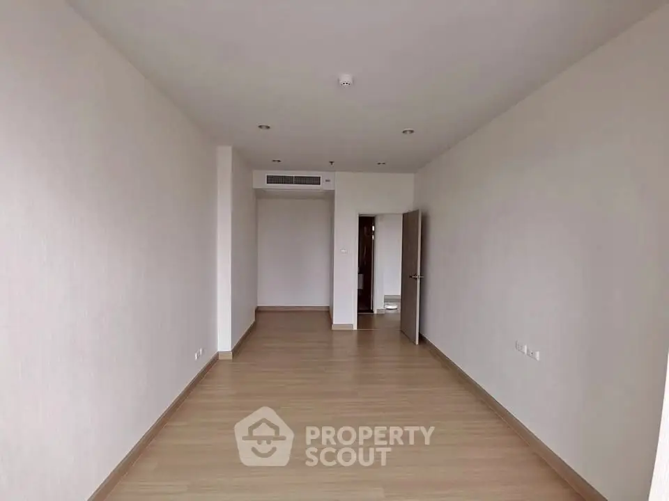 Spacious empty room with wooden flooring and neutral walls, ideal for customization.