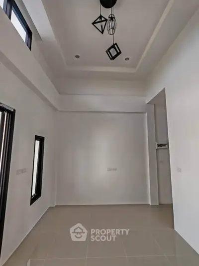 Spacious modern living room with high ceiling and elegant lighting fixtures.