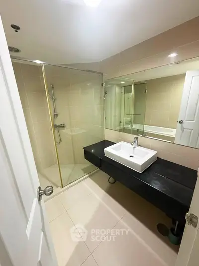 Modern bathroom with glass shower and sleek black countertop