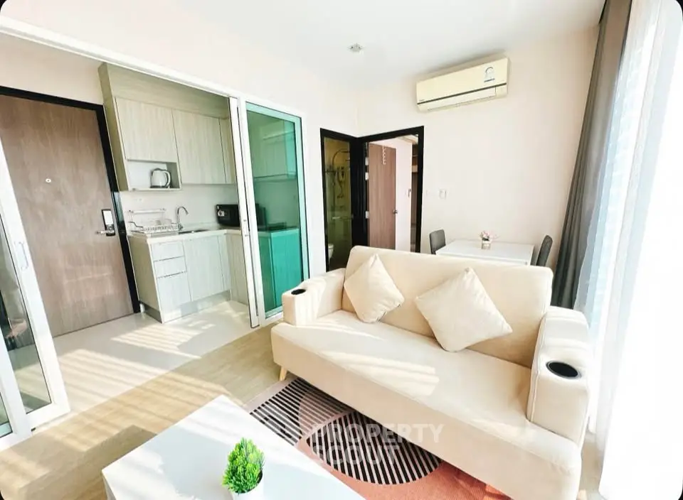 Bright modern living room with open kitchen, featuring cozy sofa and dining area, perfect for urban living.