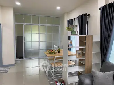 Modern living room with stylish furniture and open layout, featuring a cozy dining area and sleek shelving.