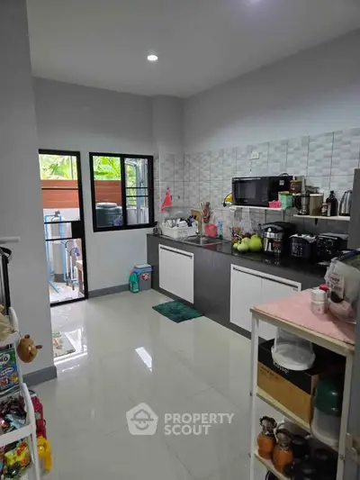 Modern kitchen with sleek cabinets and appliances, featuring a window view and open layout.