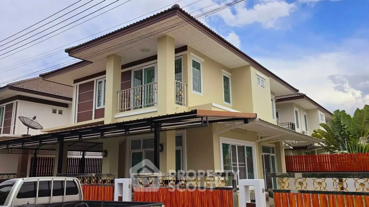 Modern two-story house with balcony and carport in a suburban neighborhood.