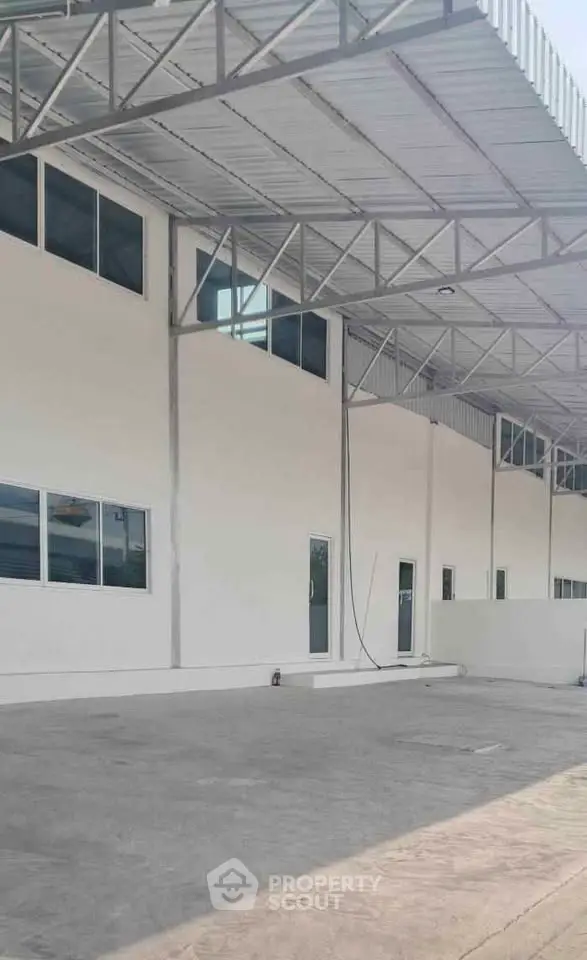 Spacious industrial warehouse exterior with modern design and ample parking space.