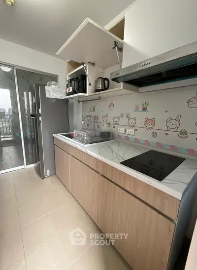 Charming kitchen with modern appliances and playful decor, featuring a sleek closed layout and balcony access.