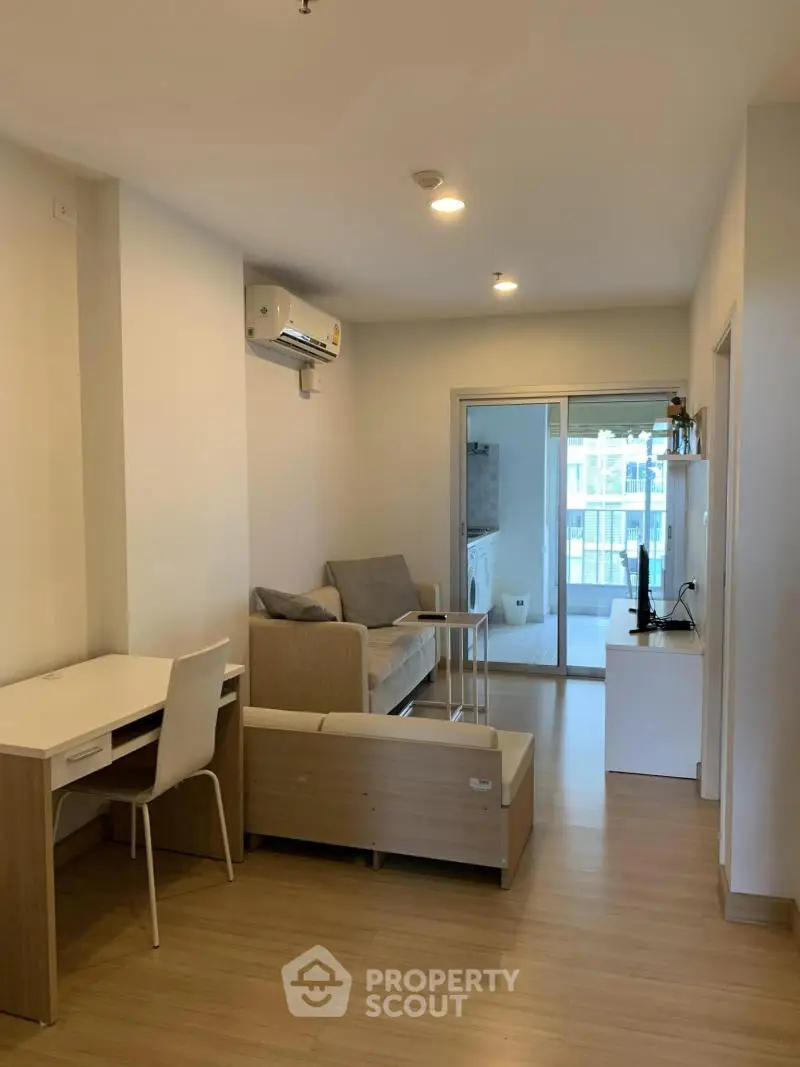 Modern living room with balcony, featuring sleek furniture and air conditioning.