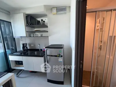 Modern compact kitchen with sleek appliances and adjacent shower area