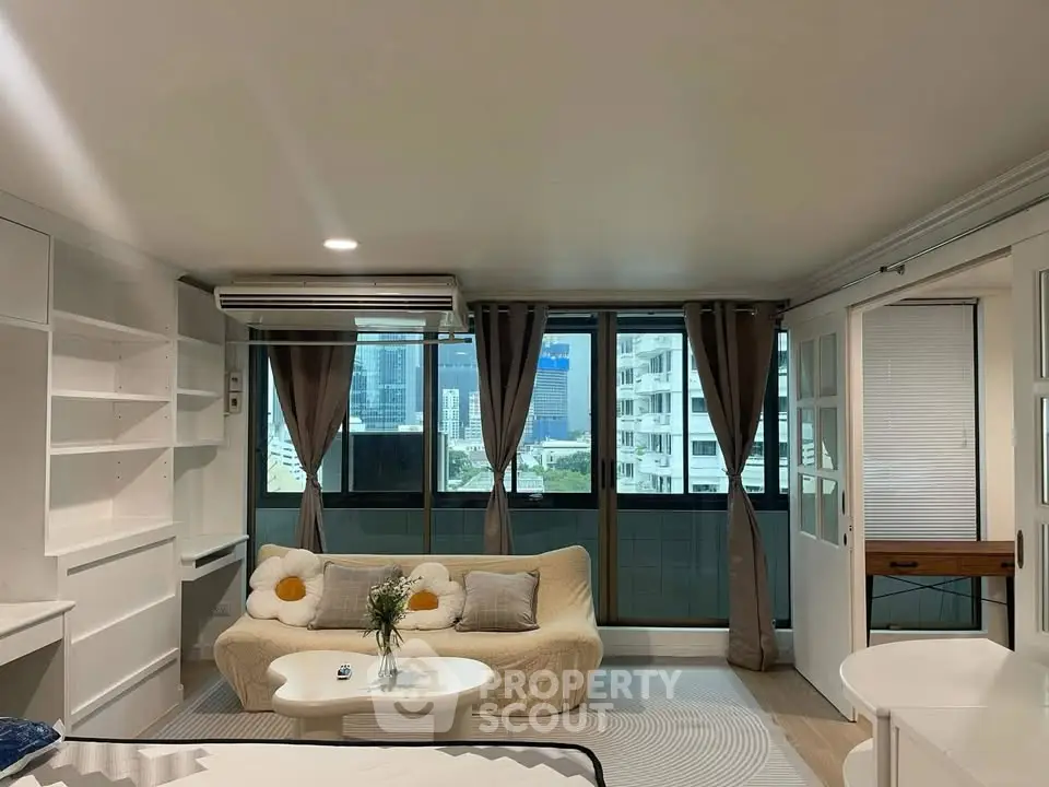 Spacious living room with large windows and modern decor in a high-rise apartment.