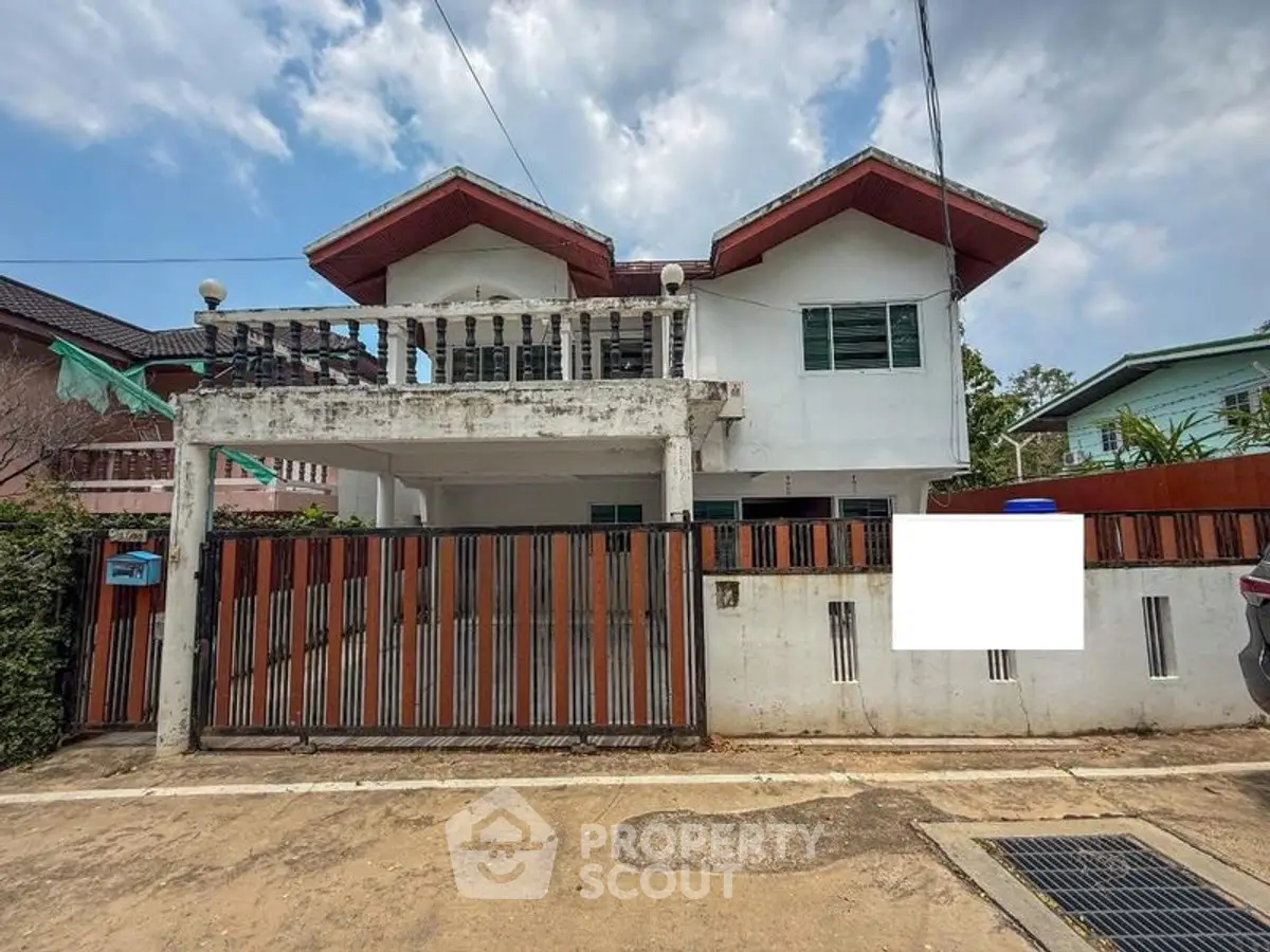 Charming two-story house with a spacious balcony and gated entrance, perfect for family living.