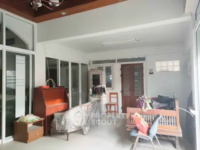 Spacious sunlit room with eclectic furniture and sliding glass doors, perfect for relaxation or entertaining guests.