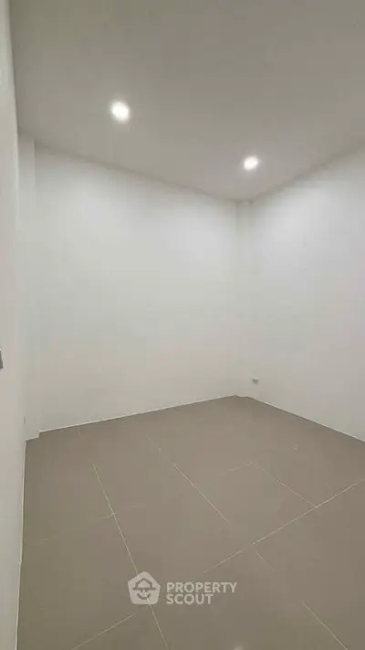 Minimalist empty room with tiled floor and recessed lighting, perfect for customization.