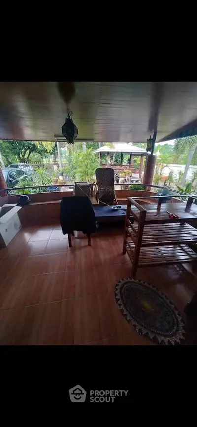 Charming covered patio with wooden furniture and lush garden view, perfect for relaxation.