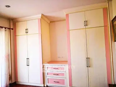 Spacious bedroom with elegant built-in wardrobes and soft pink accents.