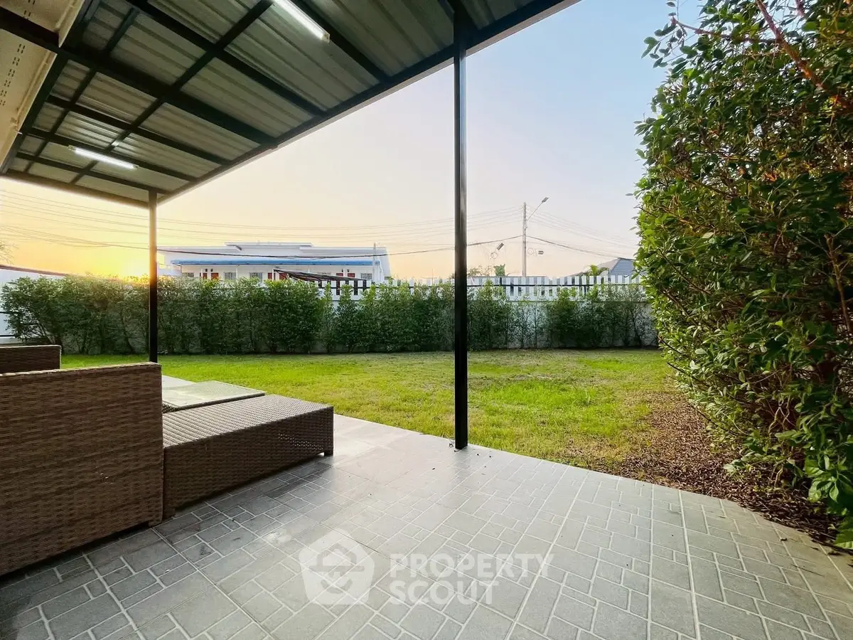 Spacious backyard with covered patio and lush greenery, perfect for outdoor relaxation.