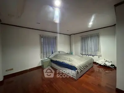 Spacious bedroom with wooden flooring and cozy bed setup