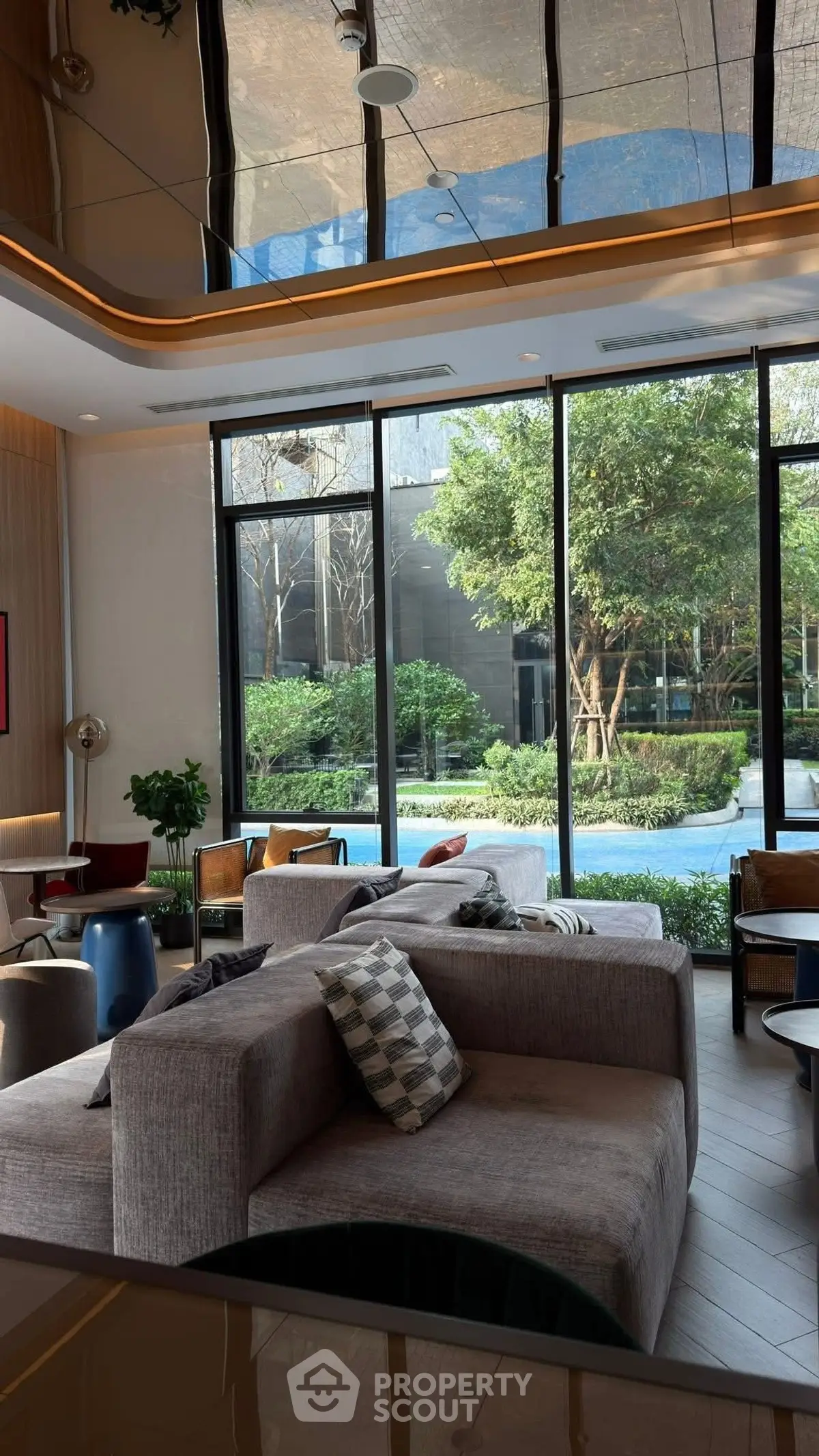 Luxurious living room with floor-to-ceiling windows and garden view, featuring modern furniture and elegant decor.