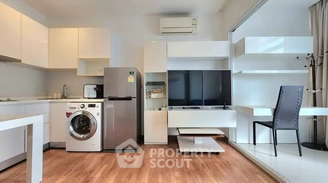 Modern open-plan living room with kitchen, featuring sleek appliances and stylish decor.