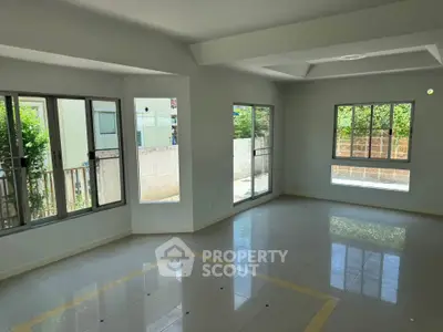 Spacious and bright living room with large windows and tiled flooring in modern home.