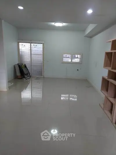 Spacious empty room with glossy tiled floor and natural light, ideal for customization.