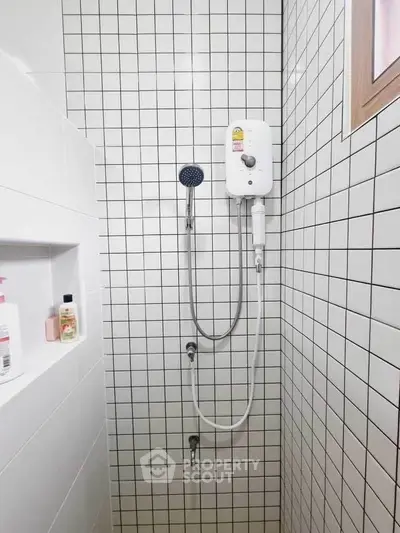Modern bathroom shower with white tiled walls and window for natural light.