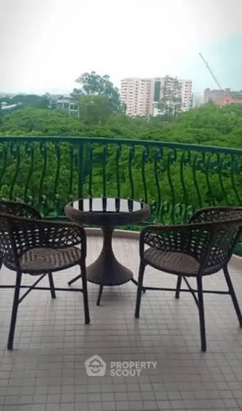 Charming balcony with lush green view and cozy seating, perfect for relaxation.