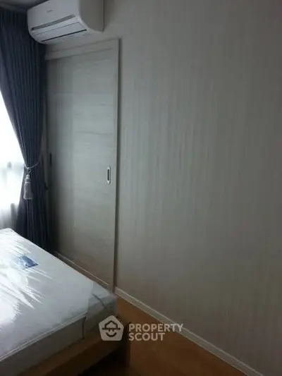 Modern bedroom with air conditioning and sliding door, featuring minimalist design and natural light.