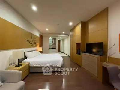 Spacious modern bedroom with cozy lighting and stylish decor, featuring a comfortable bed and sleek wooden furnishings.