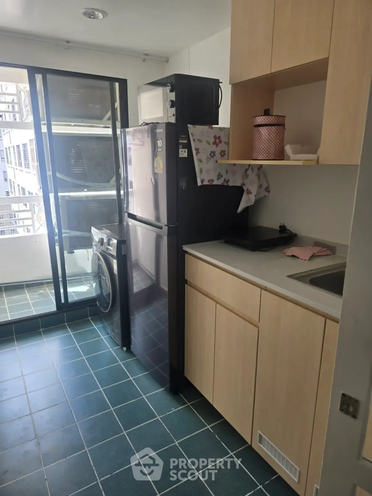 Modern kitchen with sleek appliances and balcony access in urban apartment.