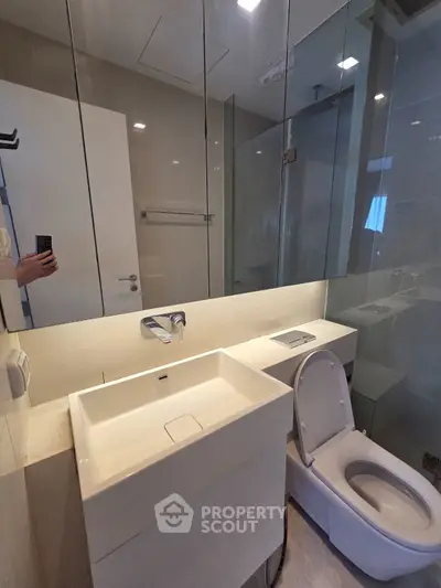 Modern bathroom with sleek fixtures and glass shower enclosure in a contemporary apartment.