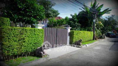 Charming residential entrance with lush greenery and decorative statues