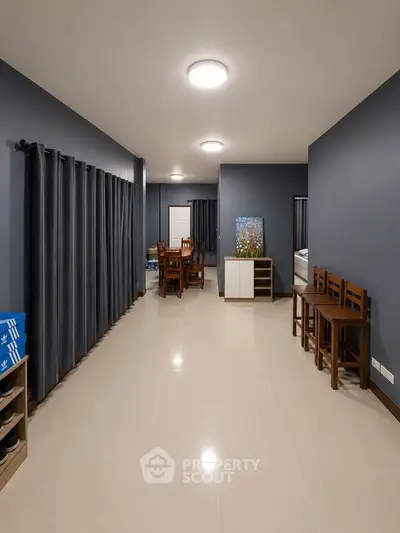 Spacious modern living room with sleek tile flooring and elegant dark curtains, perfect for family gatherings.