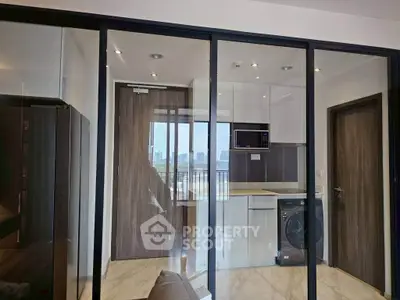 Modern apartment with glass partition, sleek kitchen, and city view balcony.