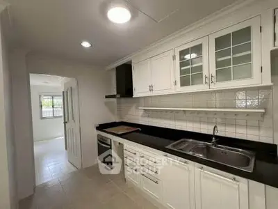 Modern kitchen with sleek black countertops and white cabinetry, featuring an oven and spacious layout.