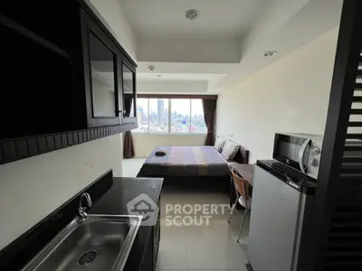 Modern studio apartment with city view, featuring compact kitchen and cozy sleeping area.