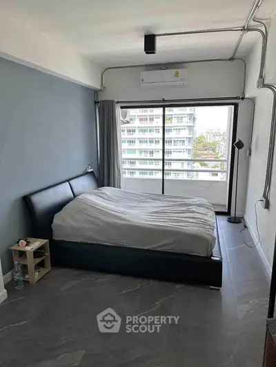 Modern bedroom with large window and city view, featuring sleek design and ample natural light.