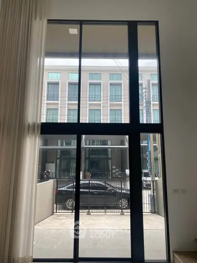 Modern high-ceiling window with urban view, perfect for natural light and contemporary living.
