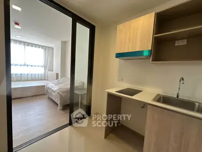 Modern apartment with open kitchen and cozy bedroom, featuring sleek design and ample natural light.
