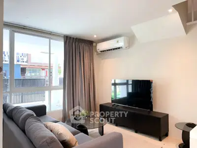 Modern living room with sleek furniture and large windows offering natural light.